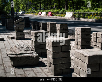 Tiles of concrete for repairing the sidewalk and road and landscaping costs on the ground composed in neat rows of several pieces in columns in the su Stock Photo