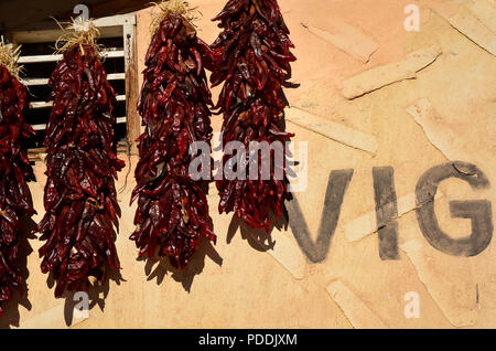 Dried red chili pepper ristras hanging on an adobe wall in Chimayo, New Mexico. Stock Photo