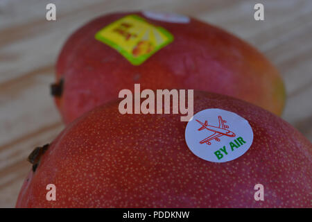 By Air sticker on fresh mango fruits in a UK supermarket.  Conceptual image, carbon footprint. Stock Photo