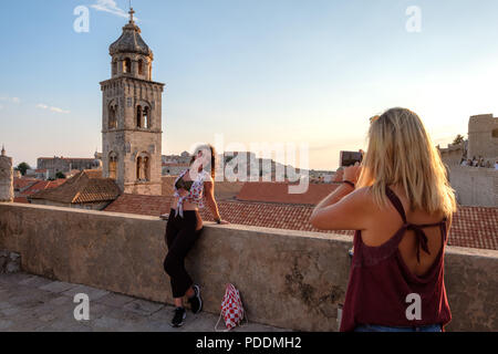 Tourists taking pictures of a friend in old town Dubrovnik with her smartphone Stock Photo