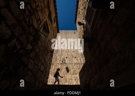 Silhouette of a tourist walking in front of the medieval city walls of Dubrovnik, Croatia, Europe Stock Photo