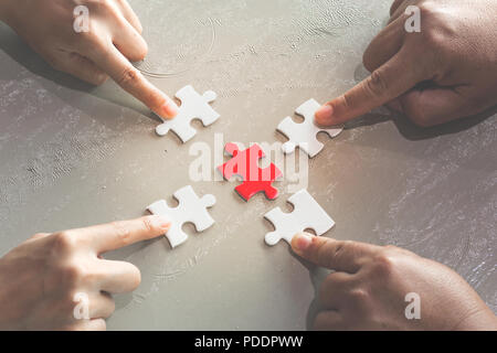 Hands of diverse people assembling jigsaw puzzle,  help support in teamwork to find common solution concept, top close up view Stock Photo
