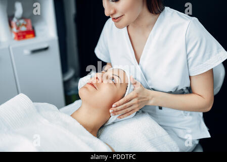 Face massage to female patient, cosmetology clinic Stock Photo