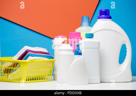 Imade of bottles of cleaning products and multi-colored towels in yellow basket isolated on red,blue background Stock Photo