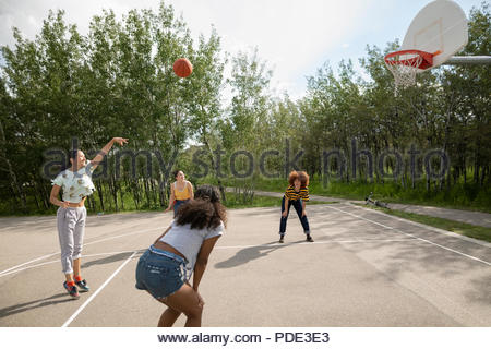 Teenage girl friends playing basketball at park basketball court Teenage girl friends playing basketball at park basketball court