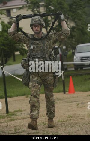U.S. Army 2nd Lt. Brian Trabun, a native of Seattle, WA, assigned to the 35th Air Defense Artillery Brigade, performs the performs lunges while hold his M4 carbine above his head during the Eighth Army Best Warrior Competition at Camp Casey, Republic of Korea, May 17, 2018. The Eighth Army Best Warrior Competition is being held to recognize and select the most qualified junior enlisted and non-commissioned officer to represent Eighth Army at the U.S. Army Pacific Best Warrior Competition at Schofield Barracks, HI. The competition will also recognize the top performing officer, warrant officer  Stock Photo