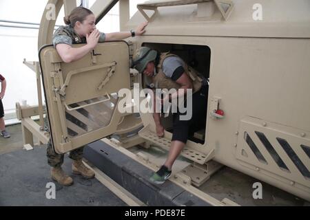 Capt. Valerie Kryger helps Coach Morra Gill participate in a simulated Mine-Resistant Ambush Protected vehicle rollover drill during Marine Corps Recruiting Command’s 2018 Coaches Workshop aboard Marine Corps Base Quantico, Virginia, May 17. The Coaches Workshop educates approximately 50 collegiate coaches from across the nation about essential Marine Corps leadership skills and programs that they can share with their student athletes based on first-hand experiences. Gill is a member of the Mid-Eastern Athletic Conference (MEAC), one of two Division I National Collegiate Athletic Association H Stock Photo