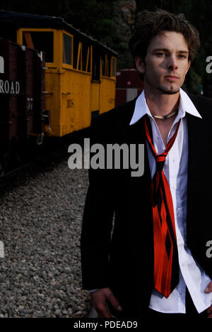 Disheveled man in a suit near an old narrow guage coal burning train after a fight.  Old west stock photos.  Exclusive Stock Photo