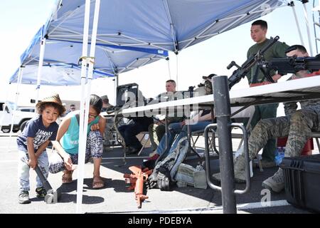 Noah Jamerson, far left, the son of Hiromi Jamerson, second from left, tests the weight of a sledge hammer as part of a Police Week demonstration at Buckley Air Force Base, Colorado, May 17, 2018. In addition to the sledge hammers, the demonstration also offered visitors an insight into other tools used by security forces members. Stock Photo