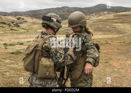 U.S. Marine Corps Sgt. Kathrine E. Cleary, left, combat instructor, School of Infantry (SOI)-West, checks a student attending Marine Combat Training (MCT) for any ammunition before exiting a range at the Marine Corps SOI-West, Camp Pendleton, Calif., May 18, 2018. MCT gives Marines with Military Occupational Specialties other than Infantry (03xx) a basic understanding of the Marine Corps' warfighting ethos, core values, basic tenets of maneuver warfare, leadership responsibilities, mental, moral, and physical resiliency in order to contribute to the successful accomplishment of their unit's mi Stock Photo