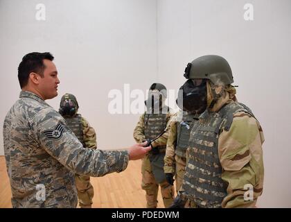 Staff Sgt. Jeremy Breillatt, emergency management craftsman with the 319th Civil Engineer Squadron, left, puffs stannic chloride gas towards Tech. Sgt. Andres Dominguez, noncommissioned officer in charge of relocations with the 319th Force Support Squadron, to test the seal of his gas mask during a readiness competition May 18, 2018, on Grand Forks Air Force Base, North Dakota. Airmen were tested on their ability to put on mission oriented protective posture gear, in addition to providing self-aid and buddy care, weapons assembly and map-reading during the competition. Stock Photo