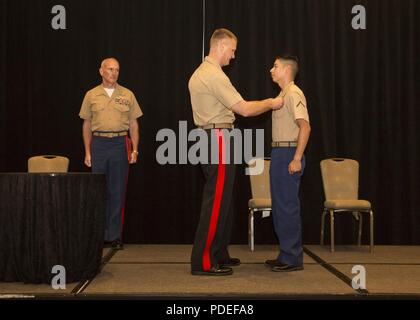 The deputy commandant for aviation, Lt. Gen. Steven R. Rudder, Headquarters Marine Corps, center, presents the Unmanned Aerial System operator insignia to Pfc. Franchesco Navarrete, an unmanned aerial vehicle operator with Marine Unmanned Aerial Vehicle Squadron (VMU) 4, 4th Marine Aircraft Wing, during the 2018 Marine Corps Aviation Association Winging Ceremony held in San Diego, May 18. Awarding of this insignia adds to the distinguished legacy of the Marine Corps’ longstanding tradition of pioneering aviation excellence while setting the standard for advancing remote combat operations and w Stock Photo