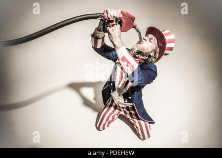 Uncle Sam sucking gasoline from a gas pump nozzle. Addicted to oil / fossil fuels. Stock Photo