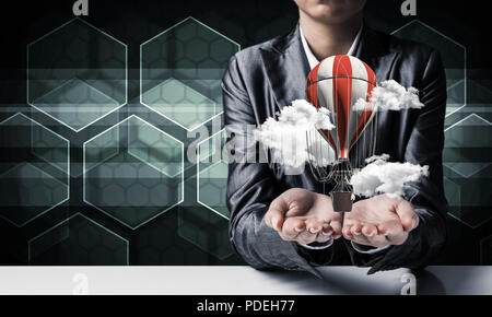 Woman presenting flying balloon in hand. Stock Photo