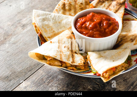 Mexican quesadilla with chicken, cheese and peppers on wooden table. Stock Photo