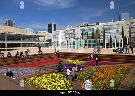 Square in Tel Aviv, Israel, surrounded by white buahaus architecture, with colorful floral public garde in the middle, peoplerelax and enjoy the place. Stock Photo