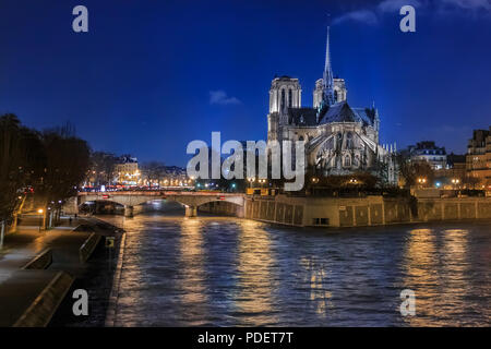 View over the river Seine onto illuminatred back side of Notre Dame de Paris Cathedral at night in, the world famous Gothic Roman Catholic cathedral i Stock Photo