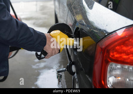 man hand refilling up gas tank of the car with green eco fuel on a filling station Stock Photo
