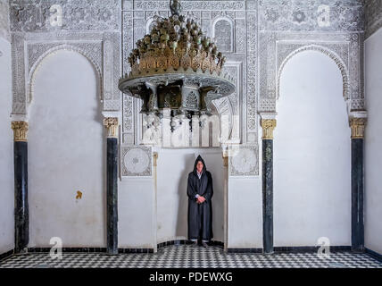 Fes, Morocco - May 11, 2013: Man in berber clothing in an alcove in the inner courtyard of the 14th century  El Attarine Medersa in Fez, Morocco Stock Photo