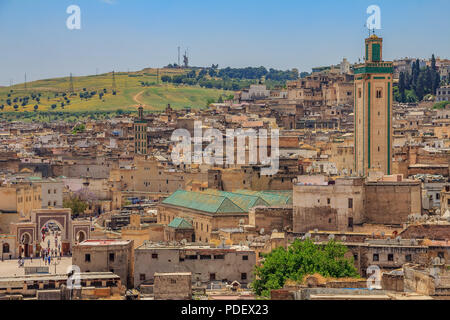 View over the ancient yellow clay rooftops of the Fez medina with a mosque in the background Stock Photo