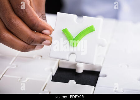 A Person's Hand Holding Piece Of Green Tick Jigsaw Puzzle Stock Photo