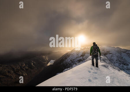mountaineer on snow-covered ridge with sunrise over the Cuillin ridge isle of Skye, figure in landscape Stock Photo