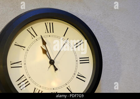Wall clock. Big clock hanging on grey wall. Light dial. Stock Photo