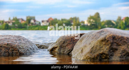 Clear river with rocks leads towards mountains lit by the sunset. Against the blue sky. Stock Photo