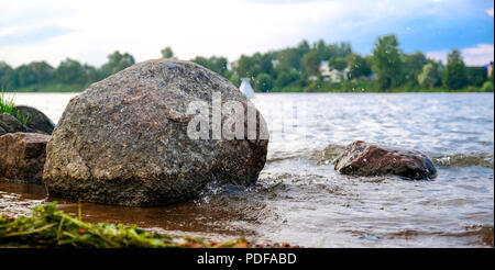 Clear river with rocks leads towards mountains lit by the sunset. Against the blue sky. Stock Photo