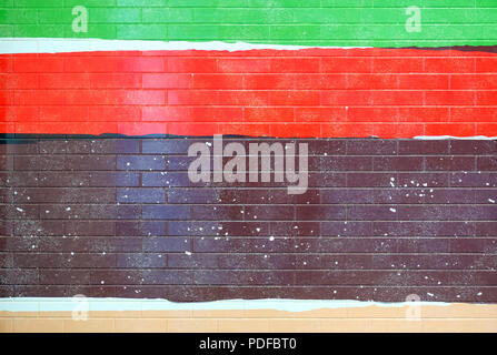 The brick wall is painted in bright colors. Detail of a painted tiled facade in vibrant colors. Stock Photo
