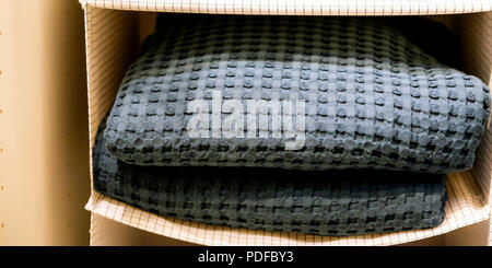 Folded towels, waffle robes, bathrobes on the shelf of the wardrobe in the hotel. Bathroom accessories Stock Photo