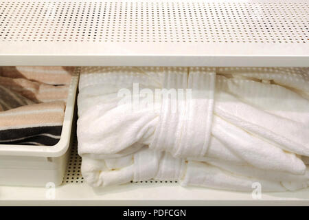 Folded towels, carpet Slippers and bathrobes on the shelf of the wardrobe in the hotel. Bathroom accessories Stock Photo
