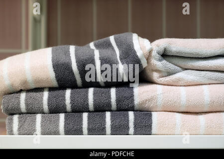 Folded towels, carpet Slippers and bathrobes on the shelf of the wardrobe in the hotel. Bathroom accessories Stock Photo