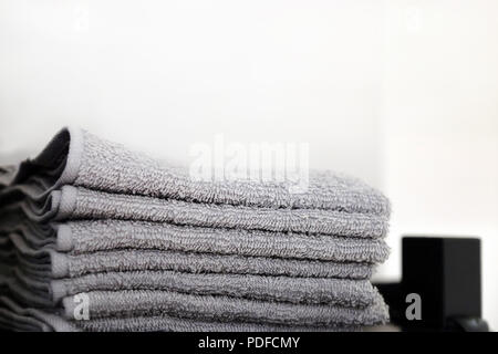 Grey and black towels are on the shelf in the bathroom. Towels hung on hooks. Bath accessories. Stock Photo