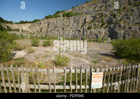 A warning sign in the entrance to a disused limestone quarry on Warton Crag in Lancashire England UK GB Stock Photo