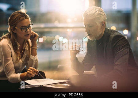 Two corporate professionals working together in office lobby. Businessman with female assistant reading few documents. Stock Photo