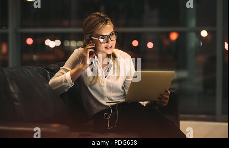 Businesswoman working late in office, doing a video call with digital tablet. Female professional working late in office and making a video call. Stock Photo