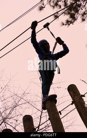 Teenager seen from the ground on the Aerial Adventure Zip Line Park at Hilton Head Island, South Carolina, United States. Stock Photo