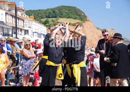 Whip the Cat Rapper and Clog, Women's English Dance Team, Performing a Rapper Sword Dance at Sidmouth Folk Festival, East Devon, UK. August, 2018. Stock Photo