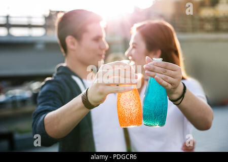Bottles with drinks being in hands of joyful young people Stock Photo