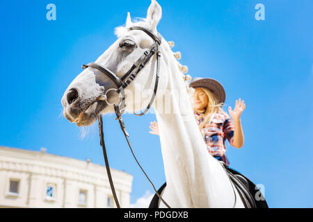 Blonde-haired cowboy girl riding horse without holding team Stock Photo
