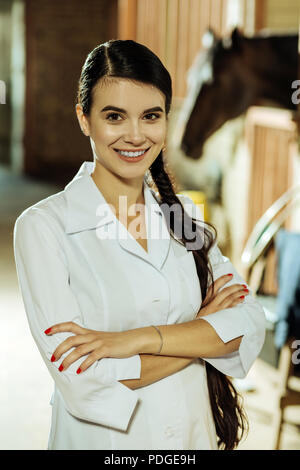 Dark-eyed smiling worker of epidemiological service Professional racehorse. Stock Photo