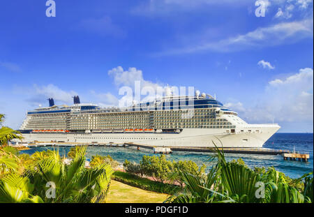 Cruise ship docked at tropical island on sunny day Stock Photo