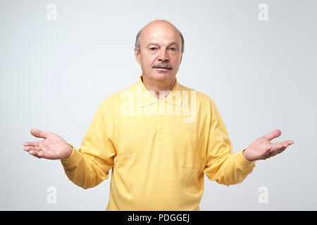 Emotional senior man not sure for something. Studio shot, gray background Stock Photo