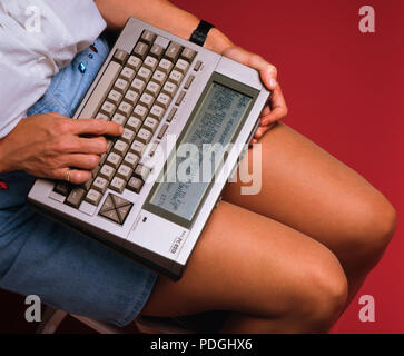 A woman holding a NEC-8201 laptop word processing computer in 1986 - one of the first portable, mobile battery operated business machines.