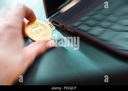 A hand plugging in a Bitcoin thumb drive into windows laptop Stock Photo