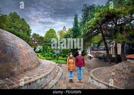 Tourist woman in brown jacket and man in red shirt standing near the dome of Public Sulfuric bath district in central Tbilisi, Georgia Stock Photo