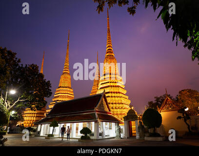 Young Couple in silhouette at Buddhist temple complex Wat Pho in Bangkok purple night sky in Thailand Stock Photo