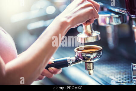 Barista woman making an espresso coffee with portafilter and coffee tamper. Stock Photo
