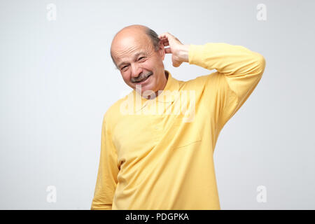 Not sure. Mature adult in yellow tshirt havinga doubt. I am confused and do not know the right way concept Stock Photo